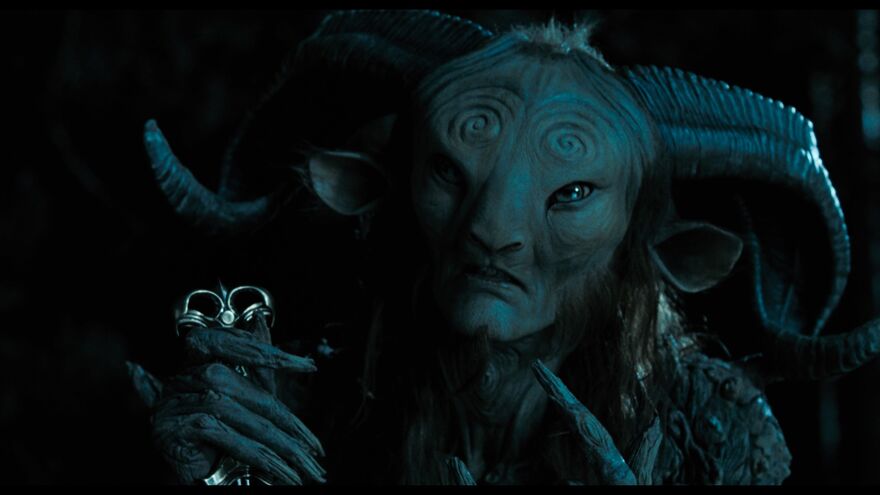 A faun holds a metal object in the darkness. 
