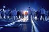 A large group of people look towards a beaming light. 