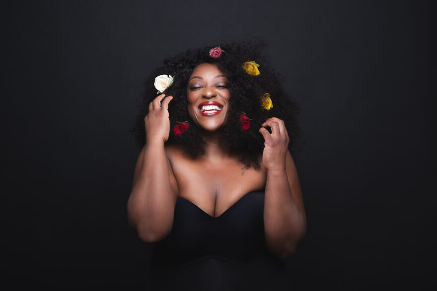 Judi Love in a black dress with flowers in her hair
