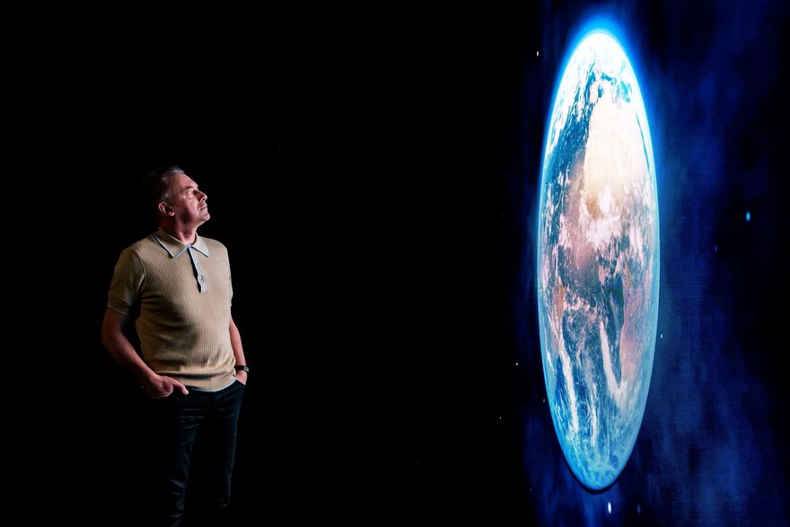 Chris Packham looks at a projection of Earth. 