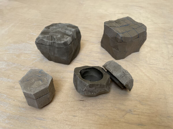 4 clay lidded boxes on a wooden floor