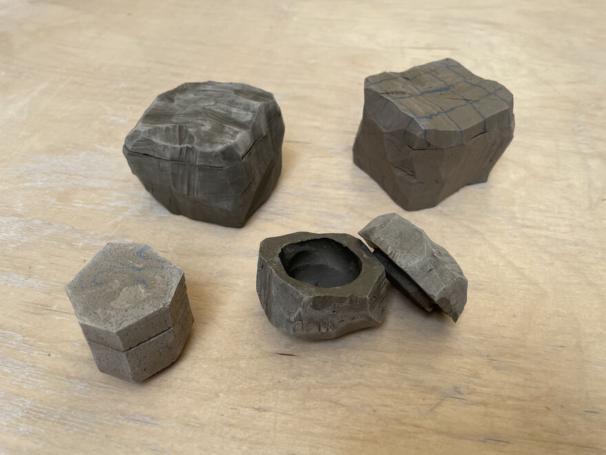 4 clay lidded boxes on a wooden floor