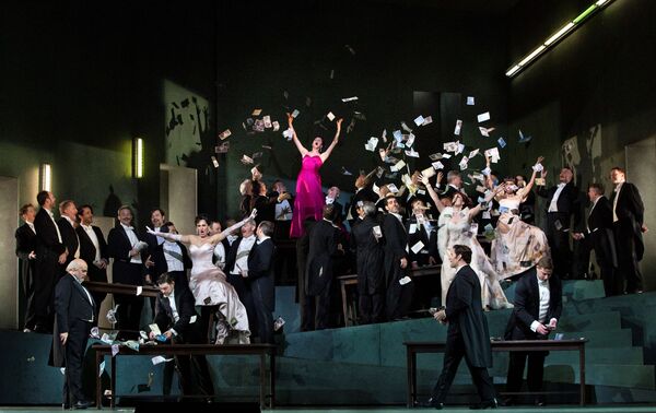 A large group of well dressed men and women. A woman in bright pink stands tall having thrown papers everywhere. 
