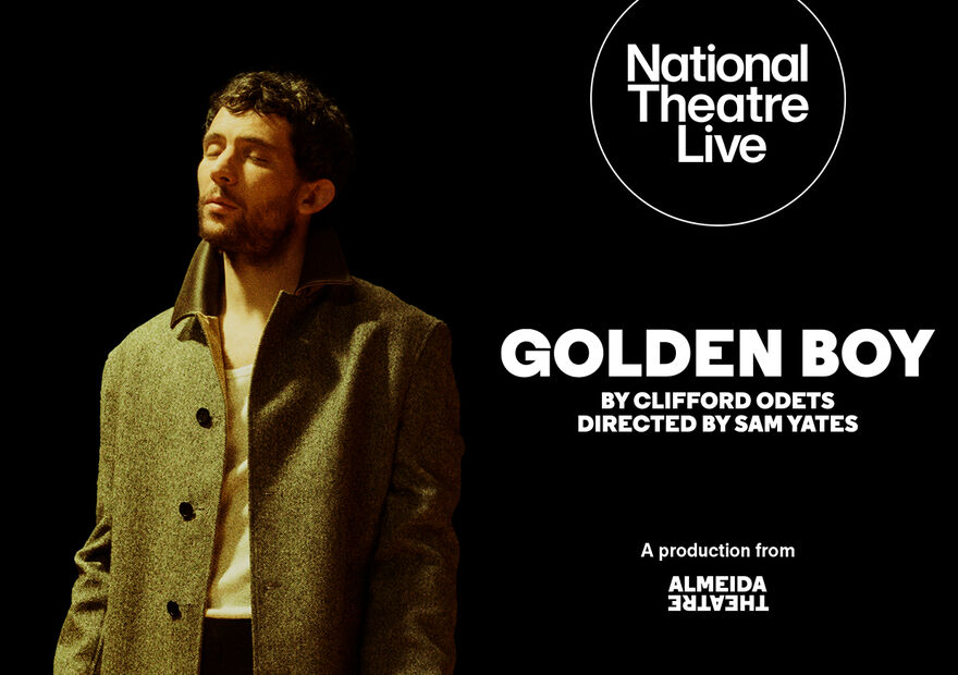 Josh O’Connor wearing a long winter coat, standing against a black background. 