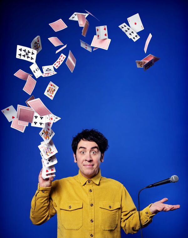 Man in a yellow cord shirt throwing playing cards in the air