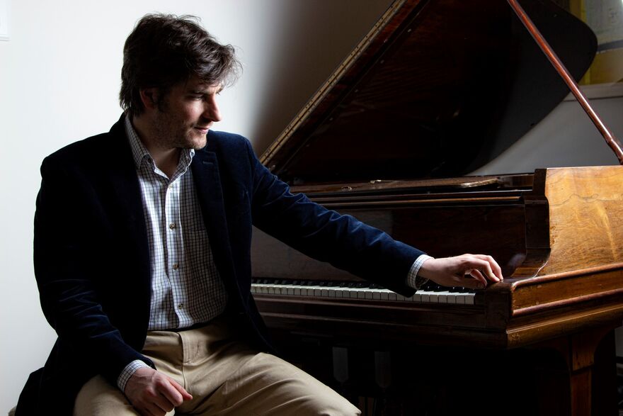Euan Stevenson sat next to a piano