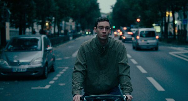 A young man cycles on the road looking despondent. A young man cycles on the road looking despondent.