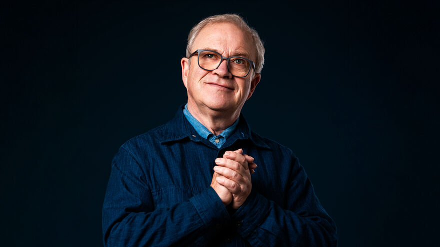Harry Enfield in a navy jacket with his hands together