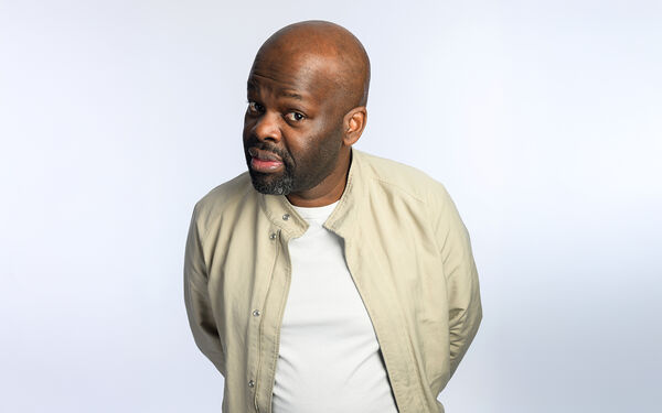 Daliso Chaponda in a light beige jacket give a sideways glance to the camera