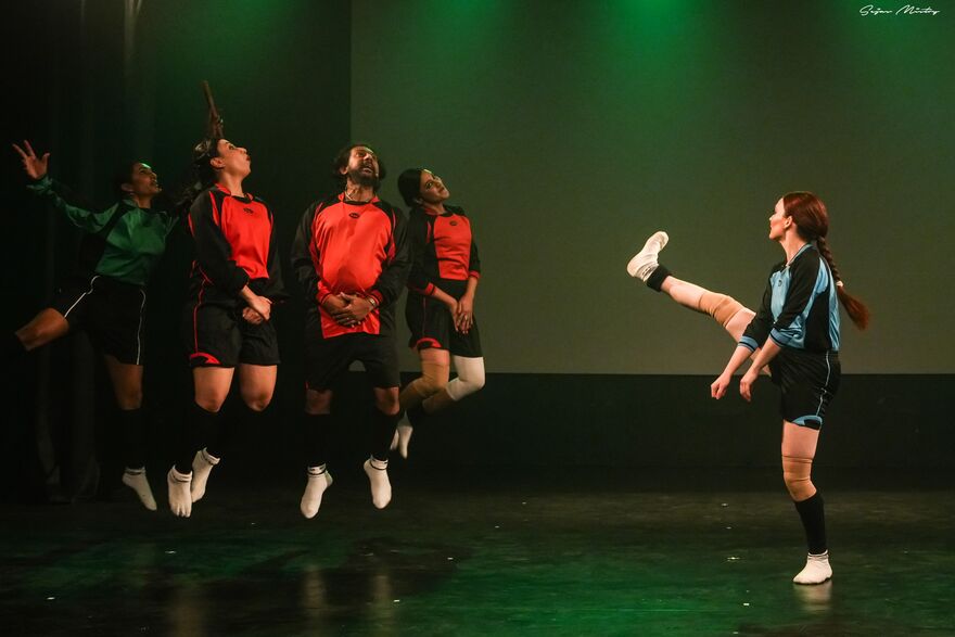 Woman mimicking kicking a ball with 4 people in a wall jumping