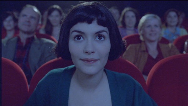 A young woman looks wide eyed at a cinema screen. A young woman looks wide eyed at a cinema screen.