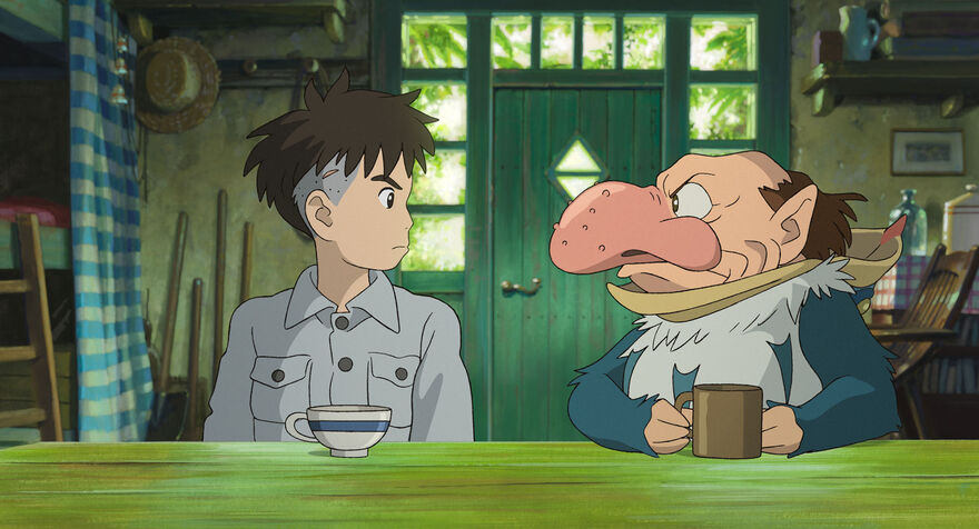 An anime image of a boy sat with a man in costume at a dining table.