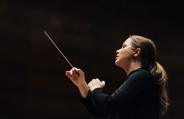 A woman conducting against a black background