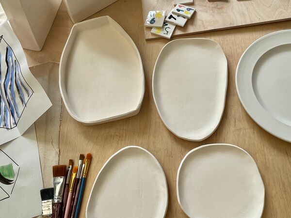 Plates laid out on a table with paint brushes 