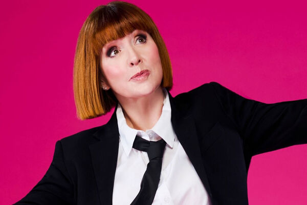 Cally Beaton in a suit and tie against a pink background