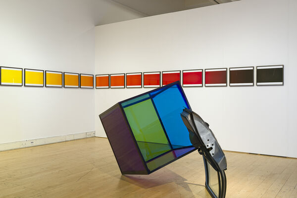 A gallery where the wall is lined with coloured images fading from yellow to red with a semi-transparent clue of blue and green
