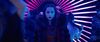 A young woman stands in a halo of light in a nightclub.