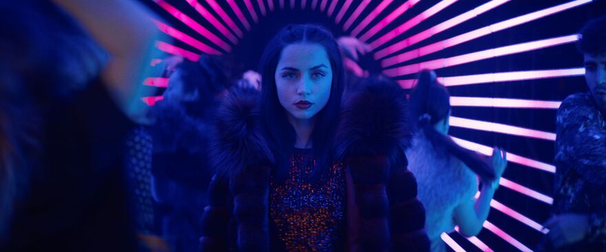 A young woman stands in a halo of light in a nightclub.