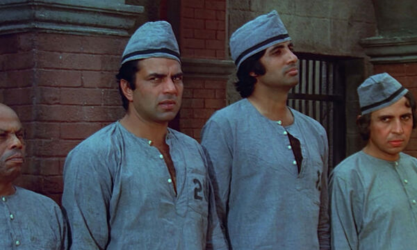 Four men in prisoner clothing standing against a wall