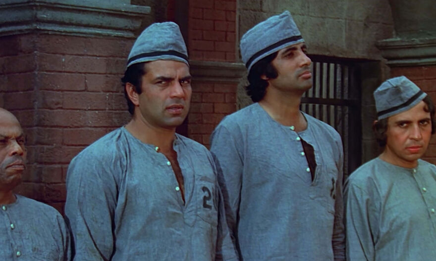 Four men in prisoner clothing standing against a wall