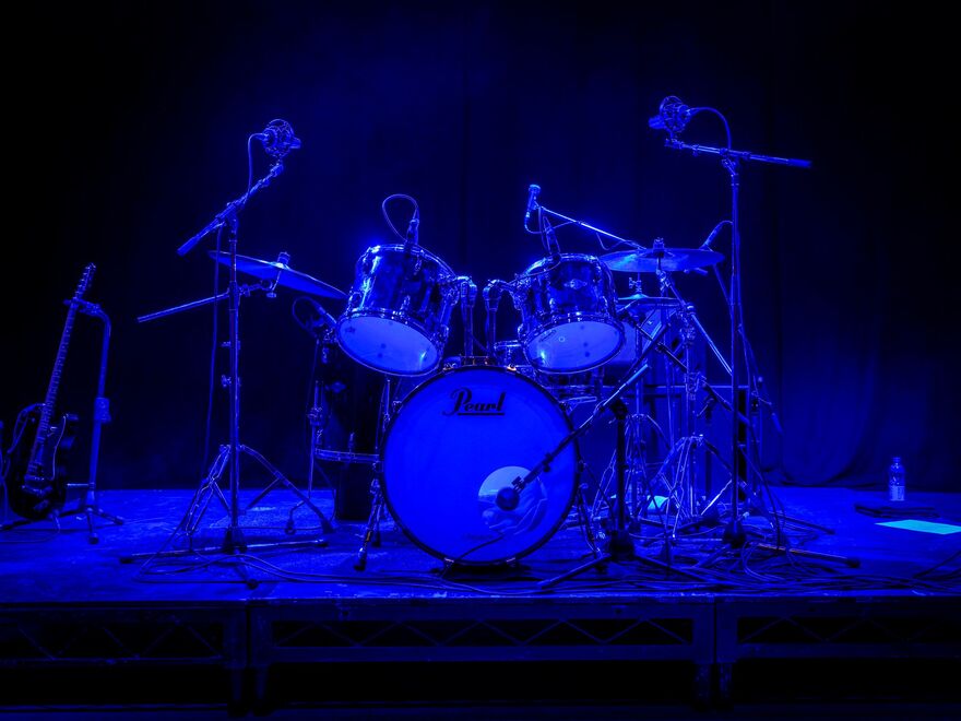 Drum kit on a dark stage lit in blue light
