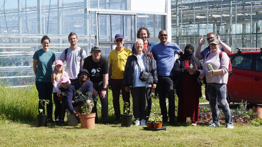Group of people standing in a garden surrounded by greenery