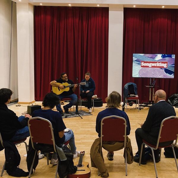 People sat on chairs in a circle at a songwriting class 