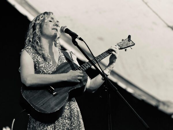 Black and white image of Lauren South  singing and playing a guitar