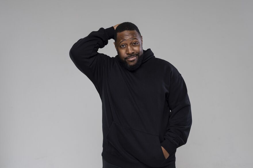 Aurie Styla in a black hoodie with one hand on his head with another in his pocket