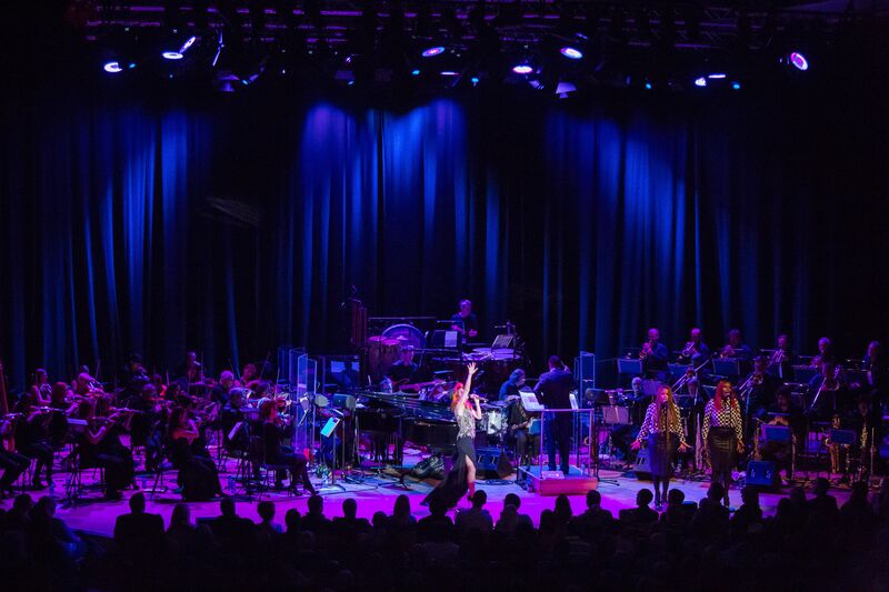 Butterworth Hall stage in purple light with a whole orchestra on the stage and a singer 