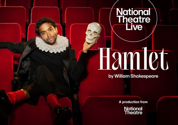 Hiran Abeysekera as Hamlet sitting in a red theatre seat holding a skull. 