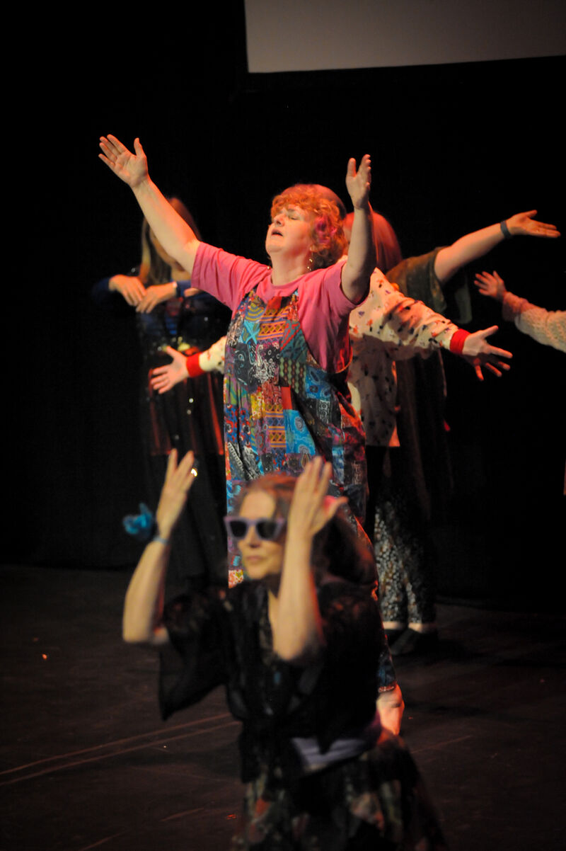 Elders dance performers in colourful clothing standing with their arms up