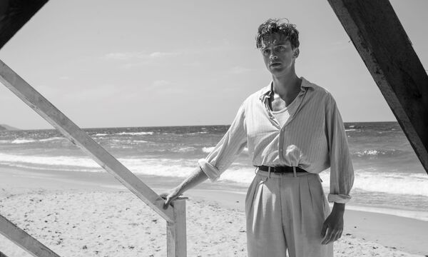 A black and white image of a young man at the beach.