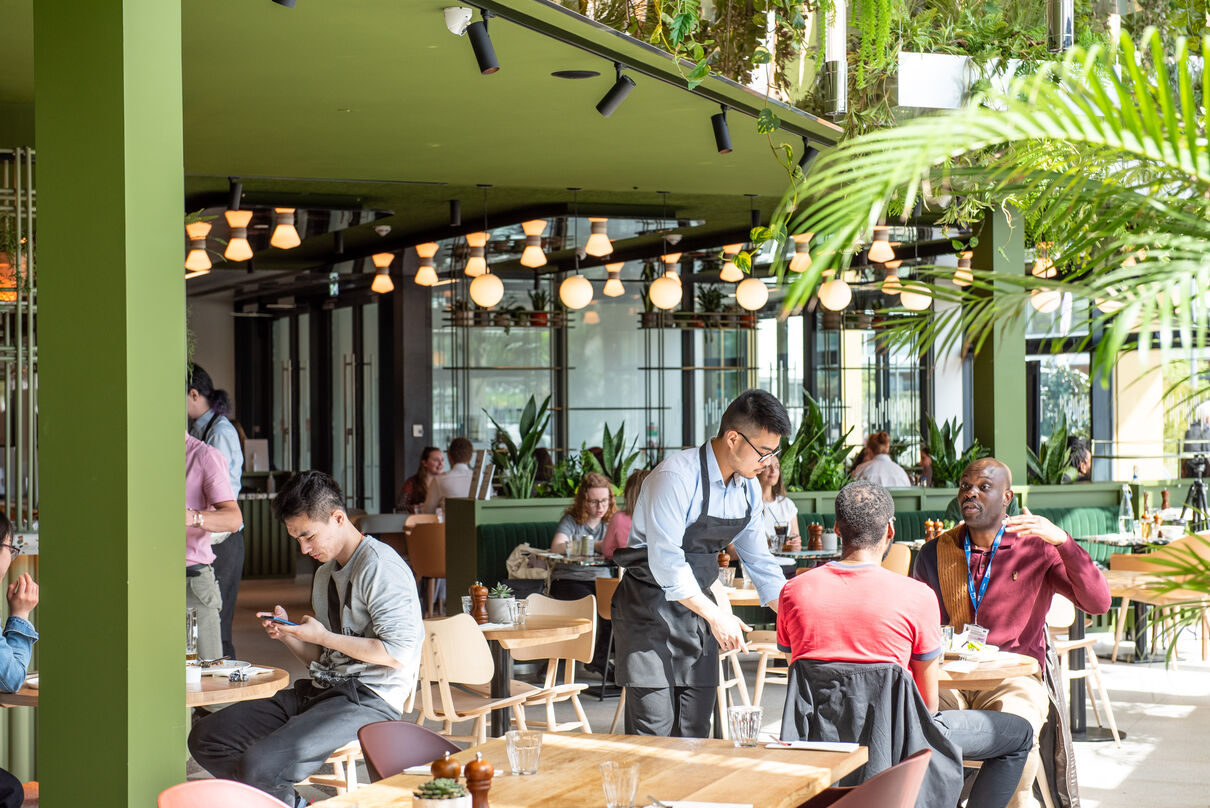 Benugo restaurant in Warwick Arts Centre with a waiter serving a two customers sat at a table