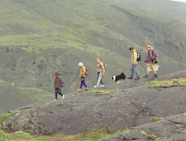 A family walk together on a mountainside with their dog. 