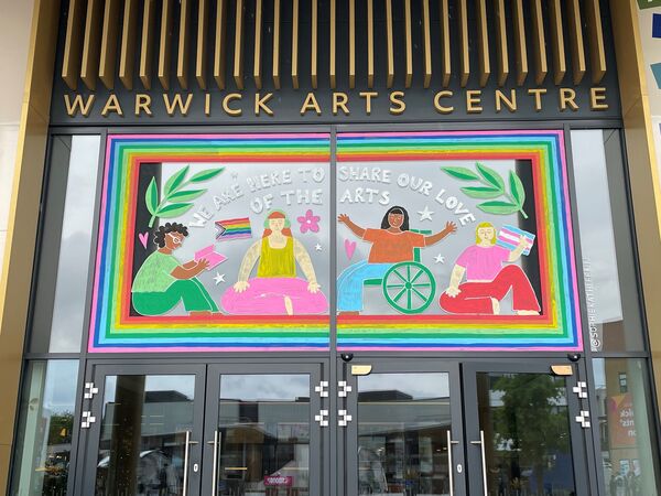 Pride mural by Sophie Kathleen at Warwick Arts Centre's main entrance window. Reads 