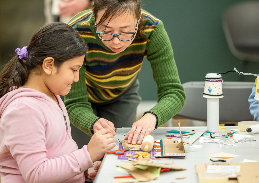 Woman helping a young girl with arts and crafts