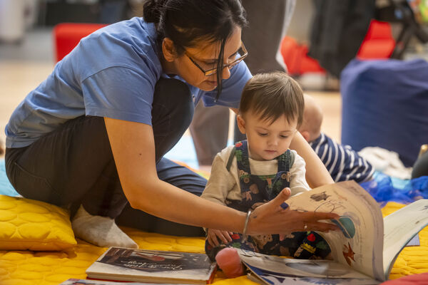 A woman reading to a young child during a Mini Creatives workshop. A woman reading to a young child during a Mini Creatives workshop.