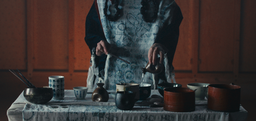 Person wearing an apron behind a table with a selection of cups and bowls