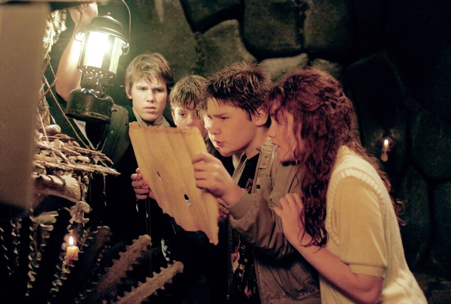 A group of four children gather in front of a treasure map and a lantern. 