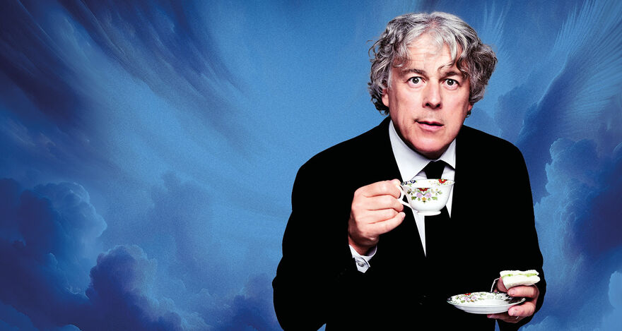 Alan Davies drinking a cup of tea against a blue cloudy background