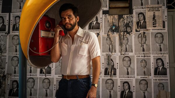 Wagner Moura on a red payphone under a yellow dome