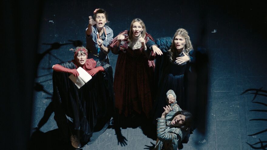 A group of actors on stage look upwards. 