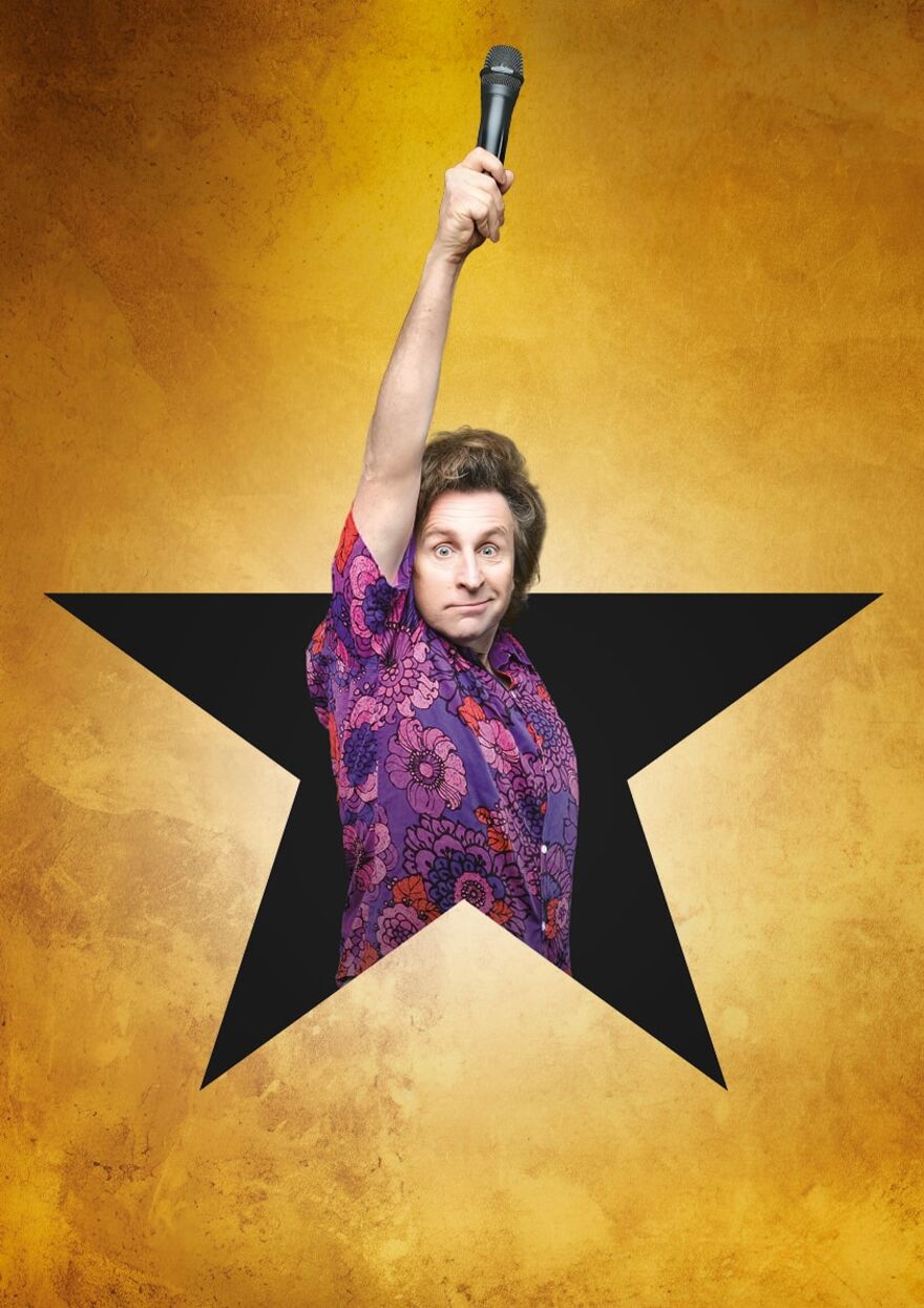 Milton Jones coming out of a star with a microphone held above his head