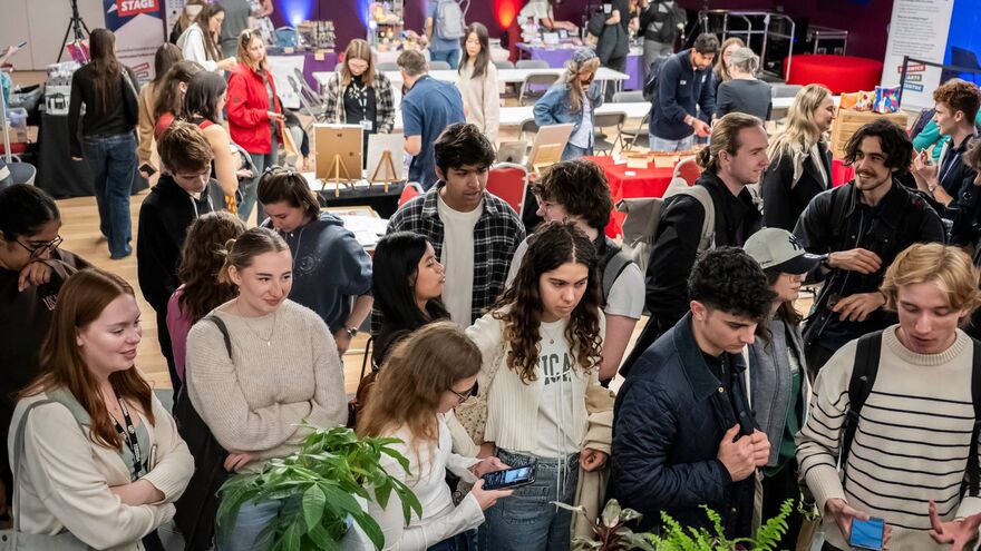 People browsing craft, gift, and book stalls inside a maker's market.