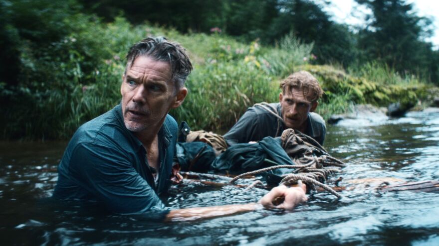 Two men wade in a river looking apprehensive. 