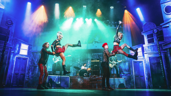 Dancers jumping on stage in front of a band