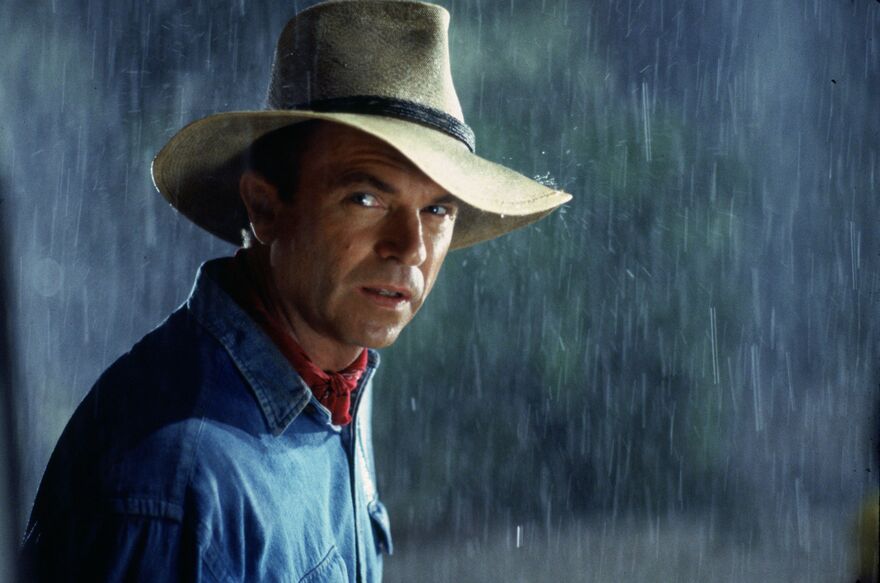 A man looks to camera as rain pours. 