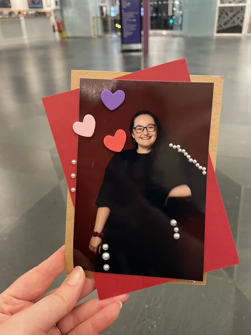 A photograph of a piece of artwork created by a participant. They have placed a portrait of themself taken by photographer Ayesha Jones in the centre, with two pieces of red and pink card behind it, positioned at different angles. 