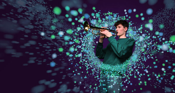 Teen boy playing trumpet surrounded by colourful blurred circles